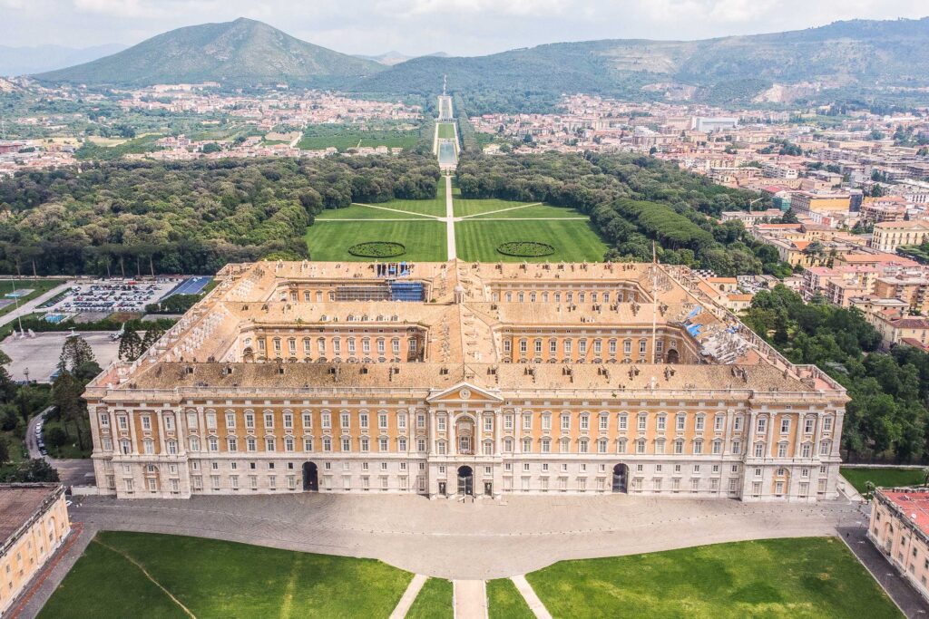 Veduta aerea della Reggia di Caserta con giardini e paesaggio circostante.