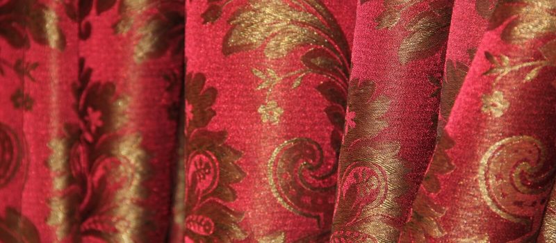 Tenda di tessuto rosso con motivo floreale dorato.